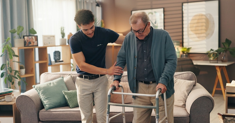Old man, caregiver and help with walker in home for mobility support, assistance or rehabilitation. Health worker, senior person and walking guide in assisted living facility for balance and recovery